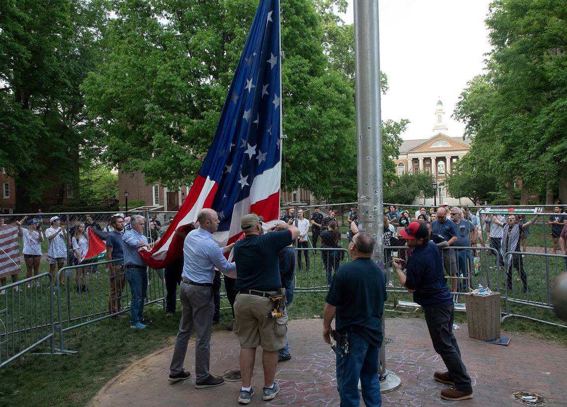 People watch as UNC-Chapel Hill administrators and facilities services staff raise an American flag behind a fenced enclosure on the campus quad on Tuesday, April 30, 2024. UNC-Chapel Hill police charged 36 members of a pro-Palestinian “Gaza solidarity encampment” Tuesday morning after warning the group to remove its tents from campus or face possible arrest, suspension or expulsion from the university. Earlier in the afternoon, protesters took an American flag down from the flagpole and then mounted a Palestinian flag in its place. Kaitlin McKeown/kmckeown@newsobserver.com