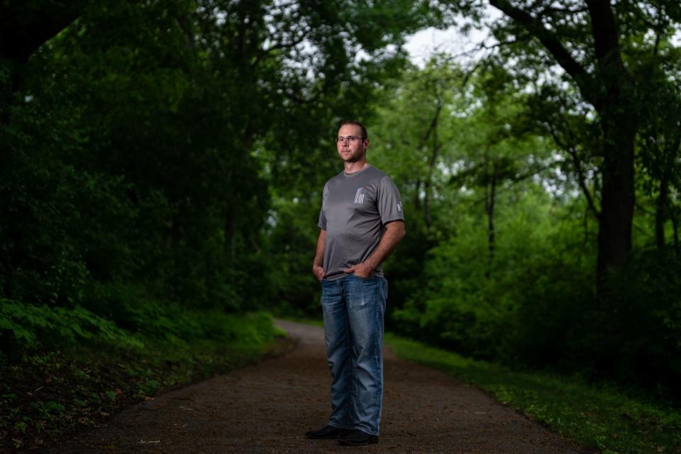 A man on a walking path surrounded by trees.