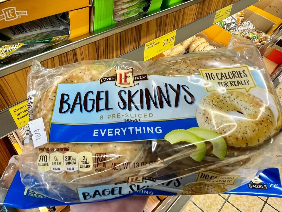 Hand holding blue and clear package of Aldi bagel things