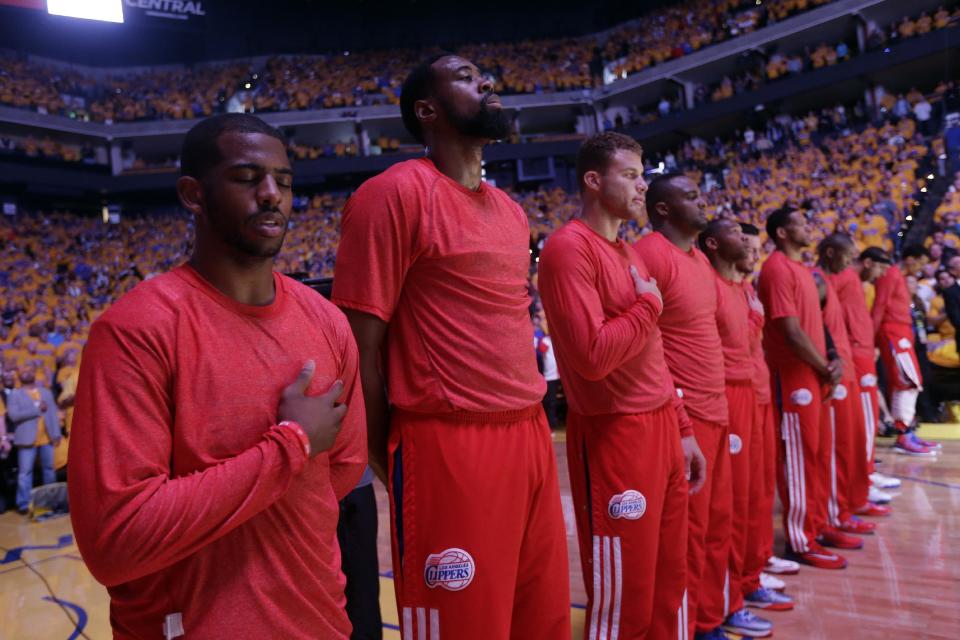 Los jugadores de los Clippers entonan el himno nacional con sus uniformes al revés en señal de protesta por los comentariosi racistas que se le atribuyen el propietario del equipo de la NBA Donald Sterling el 27 de abril del 2014 en Oakland. (AP Photo/Marcio Jose Sanchez)