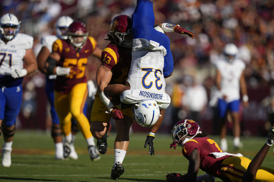 San Jose State running back Kairee Robinson (32) is grabbed by Southern California linebacker Mason Cobb (13) after he jumped over USC safety Calen Bullock (7) during the first half of an NCAA college football game in Los Angeles, Saturday, Aug. 26, 2023. (AP Photo/Jae C. Hong)