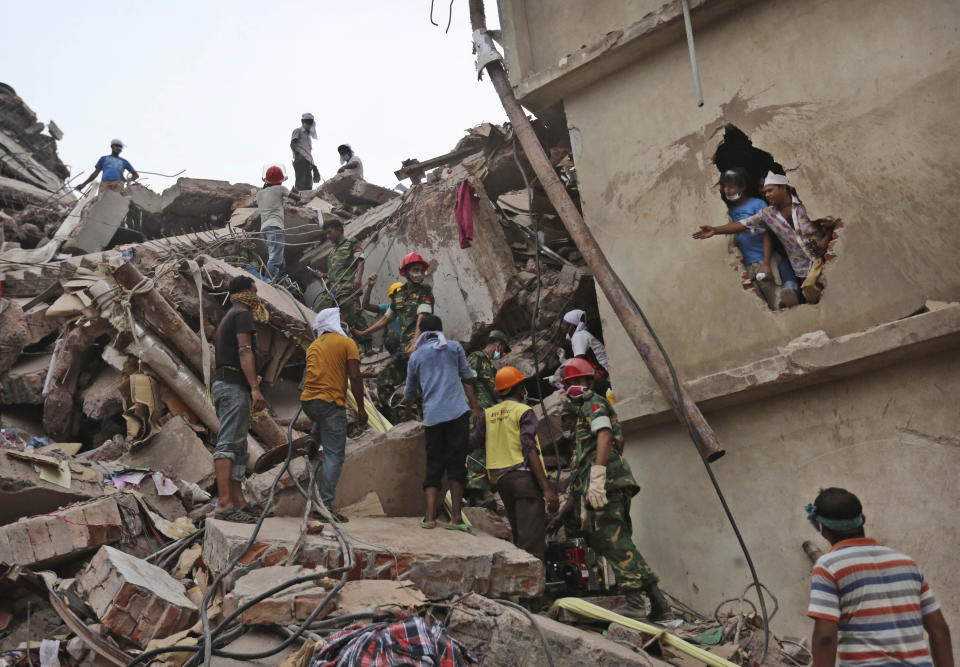 In this April 26, 2013 file photo, Bangladeshi rescue workers search for victims amid the rubble of a collapsed building in Savar, near Dhaka, Bangladesh. After more than 1,100 people died when a garment factory complex collapsed in Dhaka, Bangladesh authorities imposed more stringent safety rules. But corruption and lax enforcement have resulted in many more deaths linked to safety lapses since the 2013 Rana Plaza disaster, including a fire Thursday in an illegally-constructed high-rise office building that killed at least 25 people and left dozens more injured. (AP Photo/Kevin Frayer, File)