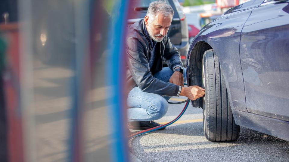 Mature Man Inflating Car Tires.