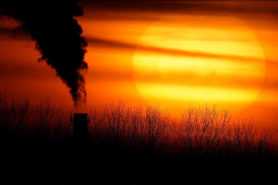 Emissions from a coal-fired power plant are silhouetted against the setting sun.