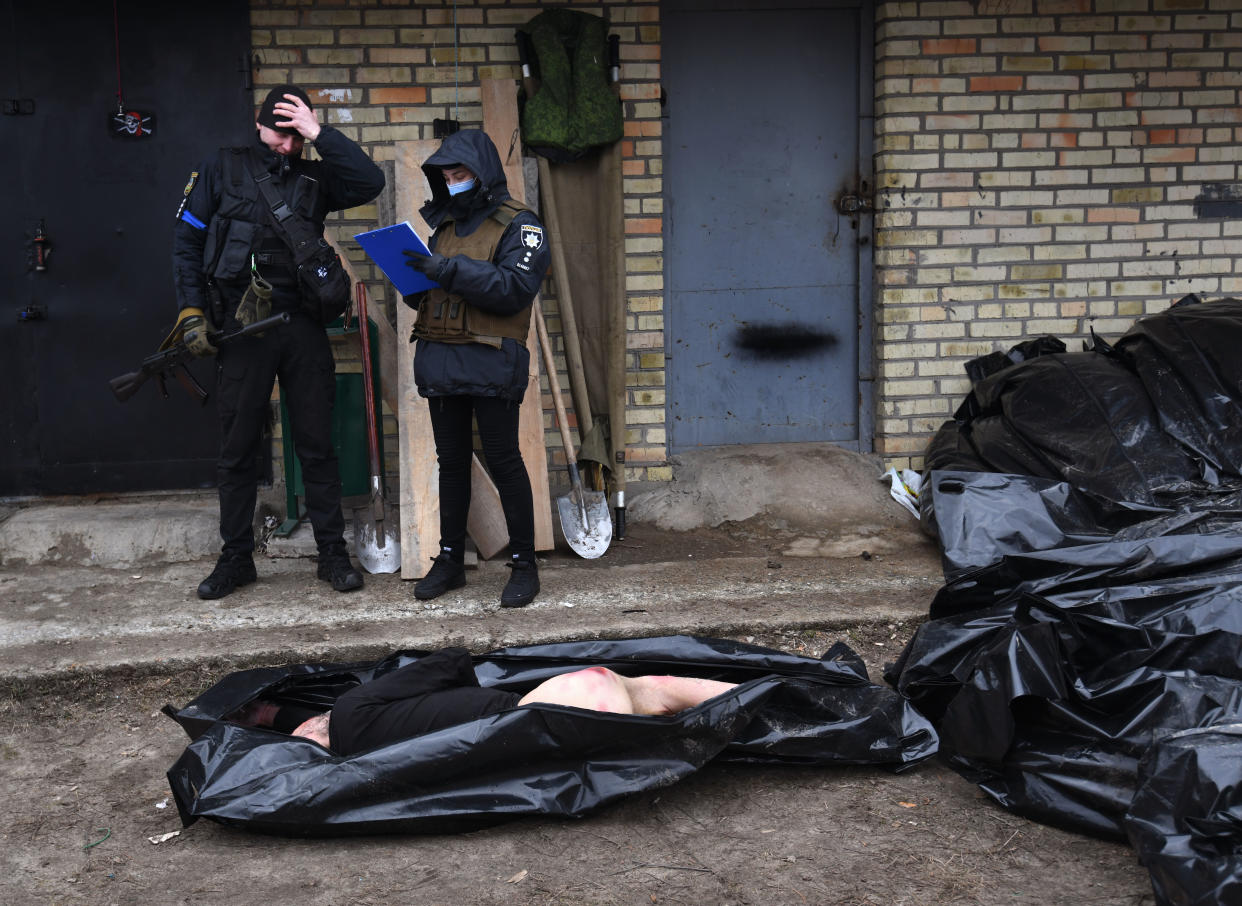 A corpse lies exposed as investigators and volunteers tally civilian deaths in Bucha after Russian troops withdrew.