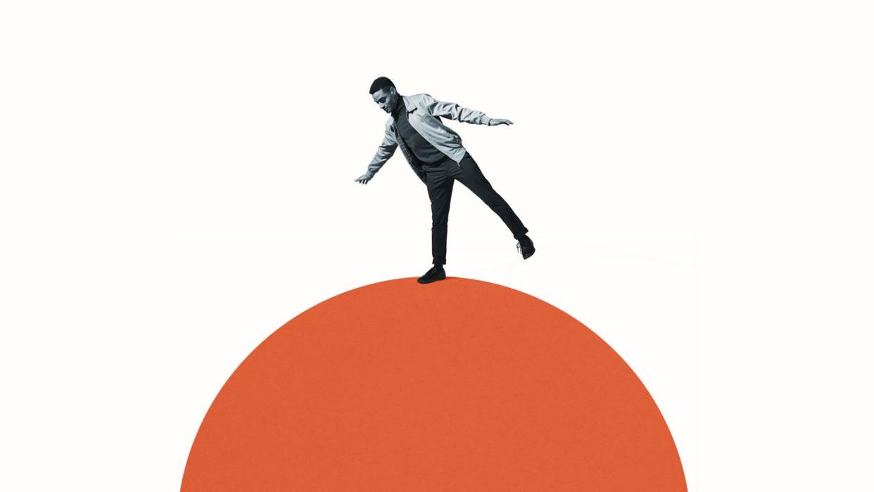 confident man balancing on orange semi circle