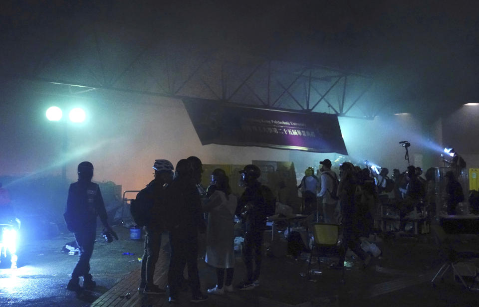 Protesters stand at Hong Kong Polytechnic University as police storm the campus in Hong Kong, early Monday, Nov. 18, 2019. Hong Kong police have stormed into a university campus held by protesters after an all-night standoff. Fiery explosions could be seen inside as riot officers entered before dawn Monday. (AP Photo/Vincent Yu)