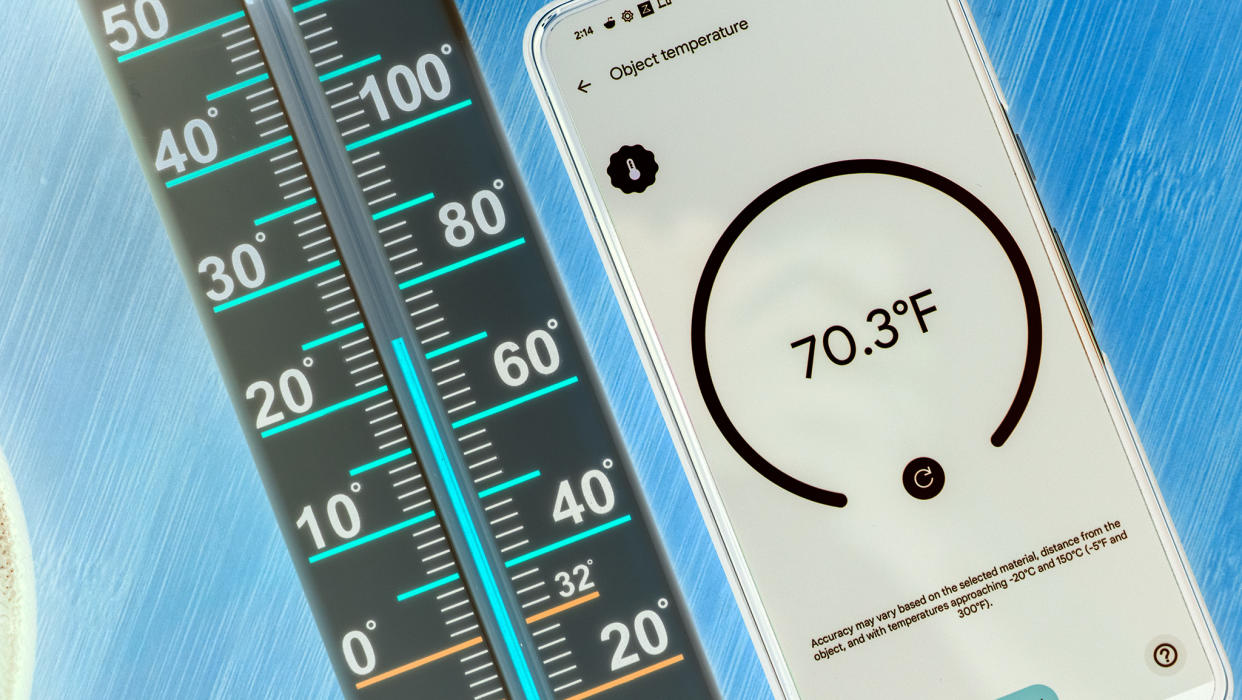  A Google Pixel 8 Pro measuring temperature next to a thermometer. 