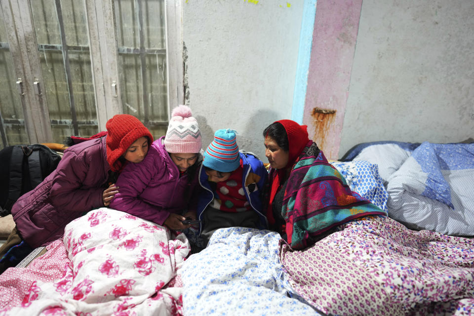 A displaced family watches their mobile phone in a temporary accommodation in a hotel, in Joshimath, in India's Himalayan mountain state of Uttarakhand, Jan. 20, 2023. Big, deep cracks had emerged in over 860 homes in Joshimath, where they snaked through floors, ceilings and walls, making them unlivable. Roads were split with crevices and multi-storied hotels slumped to one side. Authorities declared it a disaster zone and came in on bulldozers, razing down whole parts of a town that had become lopsided. (AP Photo/Rajesh Kumar Singh)
