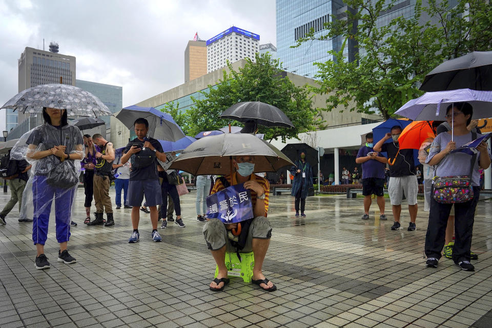 People carrying umbrellas in the rain hold placards reads "The duty fulfill by the police belong to the people" as they take part in a rally to support the Hong Kong's Police at Edinburgh Place in Hong Kong, Sunday, Aug. 25, 2019. (AP Photo/Vincent Yu)