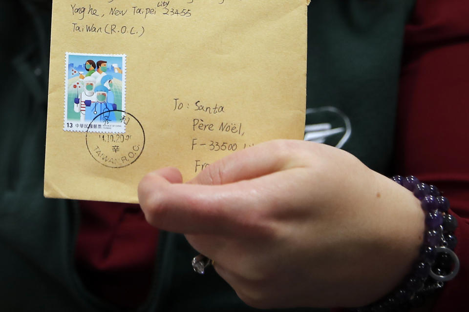 An envelope from Taiwan addressed to "Pere Noel" - Father Christmas in French - decorated with love hearts, stickers and glitter, in Libourne, southwest France, Monday, Nov. 23, 2020. Letters pouring by the tens of thousands into Santa's mailbox offer a glimpse into the worries and hopes of children awaiting a pandemic-hit Christmas. Along with usual pleas for toys and gadgets, kids are also mailing requests for vaccines, for visits from grandparents, for life to return to the way it was. The office estimates that one letter in three mentions the pandemic. (AP Photo/Francois Mori)