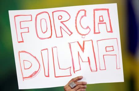 A supporter of Brazil's President Dilma Rousseff shows a sign that says "Force Dilma" during a signing ceremony for new universities at Planalto Palace in Brasilia, Brazil, May 9, 2016. REUTERS/Ueslei Marcelino