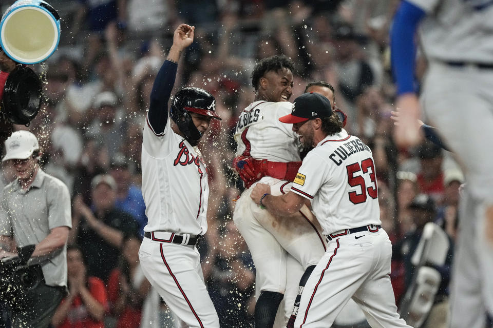 Atlanta Braves' Ozzie Albies (1) is mobbed by teammates after driving in the winning run with a sacrifice fly during the ninth inning of the team's baseball game against the Los Angeles Dodgers, Wednesday, May 24, 2023, in Atlanta. (AP Photo/John Bazemore)