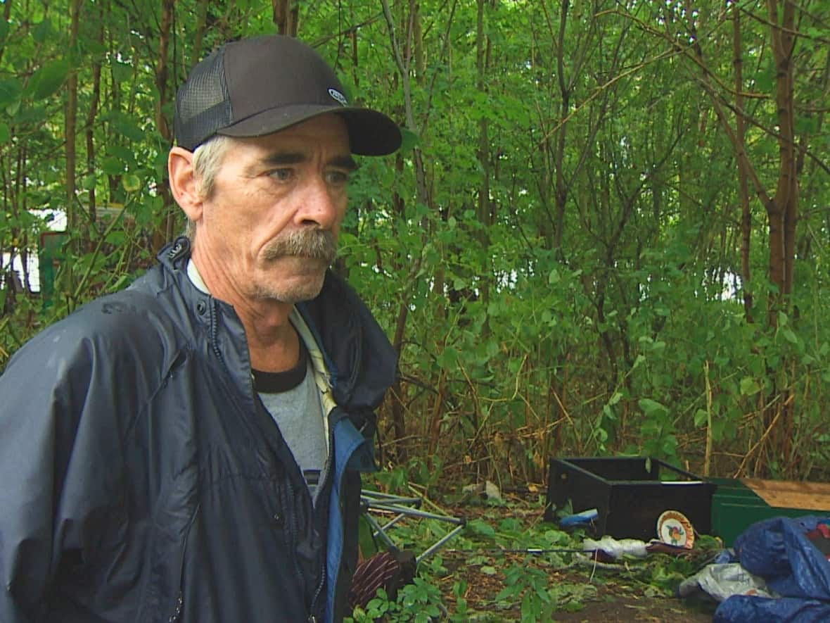 Alan DeYoung stands in front of the remains of his neighbour's camp. He said he decided to stay in his structure and not go to one of the city's emergency shelters because he suffers from PTSD and doesn't feel safe in crowds.  (David Laughlin/CBC - image credit)