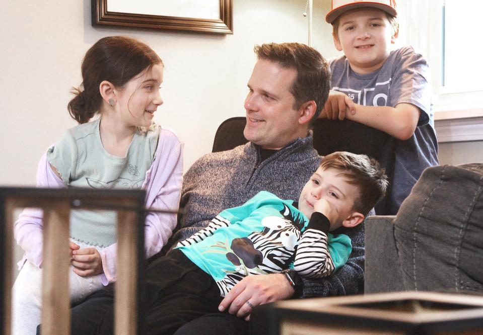 Erie resident Jay Breneman, 40, sits with his children, clockwise from left, Paige, 8, Elijah, 11, and Milo, 4, at home.