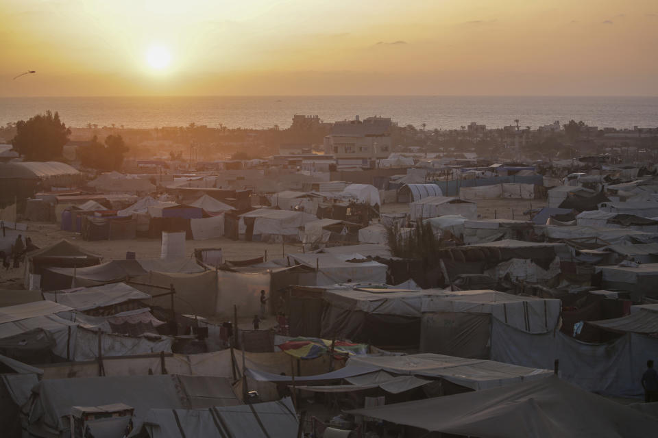 Palestinians displaced by the Israeli air and ground offensive on the Gaza Strip walk through a makeshift tent camp in Khan Younis, Gaza, Tuesday, June 18, 2024. (AP Photo/Jehad Alshrafi)