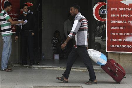 A foreign worker pulls his luggage along a street in Riyadh November 4, 2013. REUTERS/Faisal Al Nasser