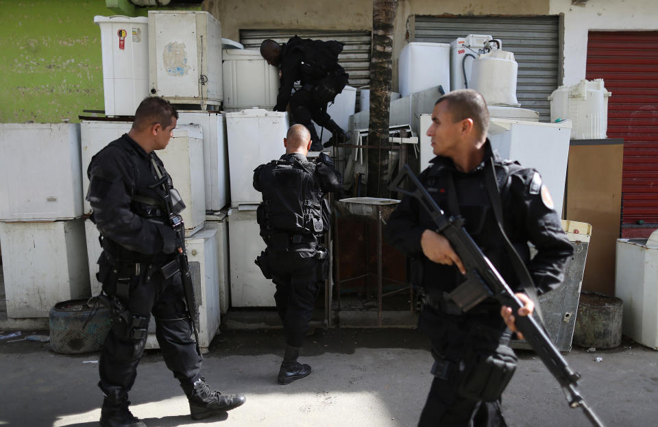 Special operations battalion Police officers search for drugs and weapons inside wash machines stored on a sidewalk during an operation against gangs of drug traffickers, in the Mare slum complex in Rio de Janeiro, Brazil, Sunday, March 30, 2014. The Mare complex of slums, home to about 130,000 people and located near the international airport, is the latest area targeted for the government's "pacification" program, which sees officers move in, push out drug gangs and set up permanent police posts. (AP Photo/Leo Correa)