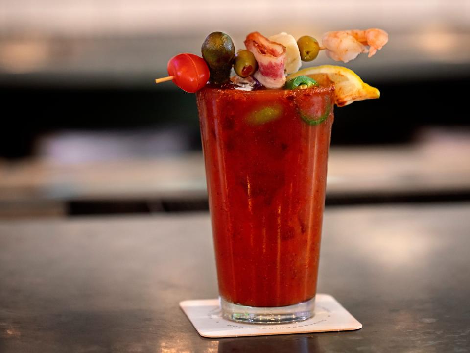 bloody mary with a bunch. of toppings sitting on a napkin on a gray counter