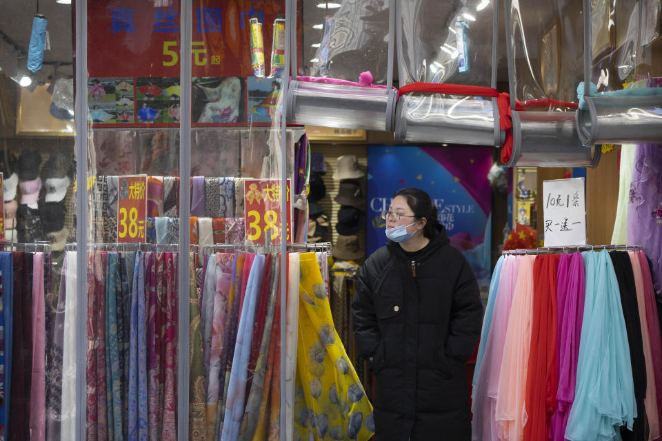 A worker waits for customers at the entrance of a clothing shop along a tourist shopping street in Beijing, Feb. 28, 2023. Chinese leader Xi Jinping's agenda for the annual meeting of the ceremonial legislature: Revive the struggling economy by encouraging consumers to spend now that severe anti-virus controls have ended. Install a government of Xi loyalists to intensify the ruling Communist Party's control over the economy and society. (AP Photo/Mark Schiefelbein)