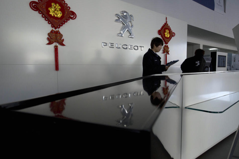 A salesperson waits for customers at the reception to a Dongfeng and Peugeot joint venture show room in Beijing Wednesday, Feb. 19, 2014. Loss-making French carmaker PSA Peugeot Citroen is getting a 3 billion euro lifeline backed by Chinese investors and the French government in a deal that will see the company's founding family hand over control after more than two centuries at the helm. Chinese automaker Dongfeng and the French government are each investing 800 million euros ($1.1 billion) in Peugeot, throwing a financial lifeline to the struggling French auto brand and possibly expanding its global presence. (AP Photo/Ng Han Guan)