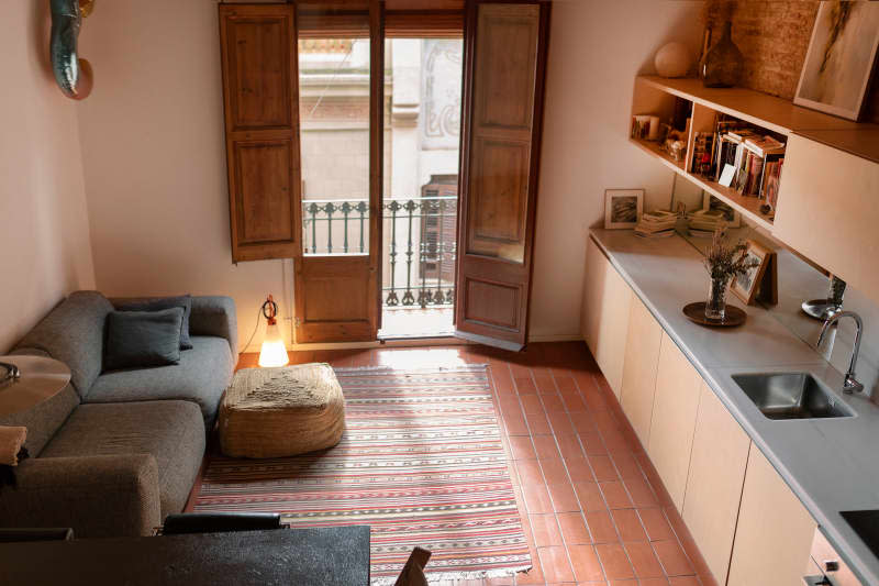 Grey sofa in living room and kitchen area of Barcelona apartment.