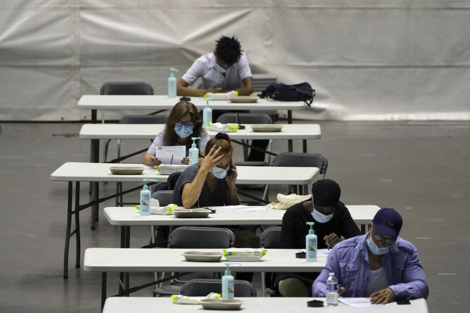 People fill out a form before receiving the Pfizer-BioNTech COVID-19 vaccine, in a vaccination center of Lyon, central France, Wednesday, July 7, 2021. French government spokesperson Gabriel Attal said the epidemic is gaining ground again in France due to the delta variant, after several months of decrease. (AP Photo/Laurent Cipriani)