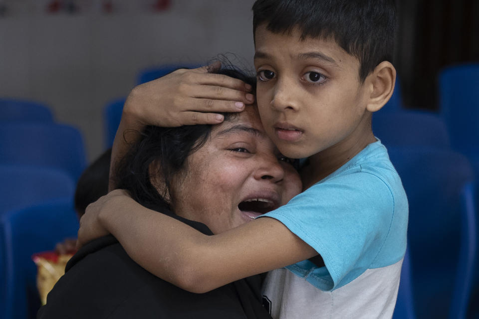 Rakibul, 6, comforts his mother Rehana mourning the death of her husband, Mohammad Zillur, at a hospital in Munshiganj, outside Dhaka, Bangladesh, Sunday, Jan. 7, 2024. Zillur, a supporter of a candidate from the ruling Awami League, was stabbed to death on Sunday as Bangladesh voted in a parliamentary election boycotted by the main opposition party. (AP Photo/Altaf Qadri)
