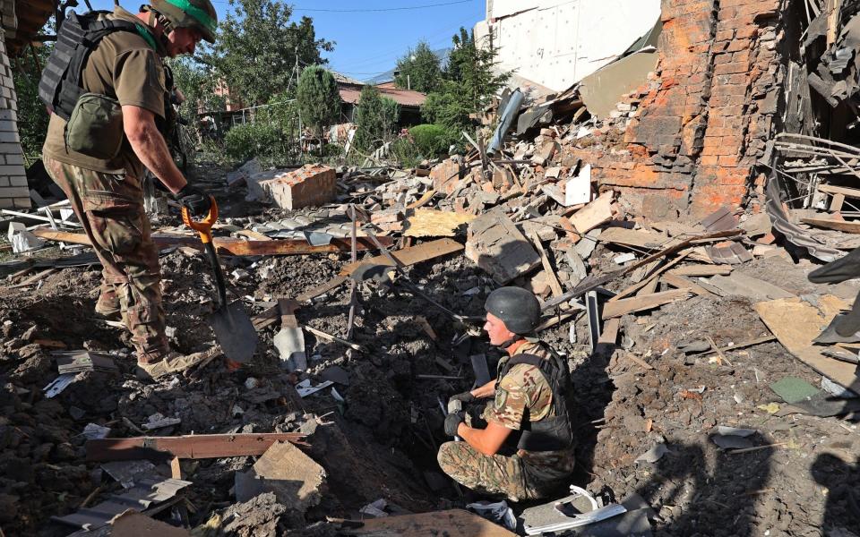 Law enforcers examine the crater from an impact in a residential area after the Russian glide bomb attack in Kharkiv on July 3