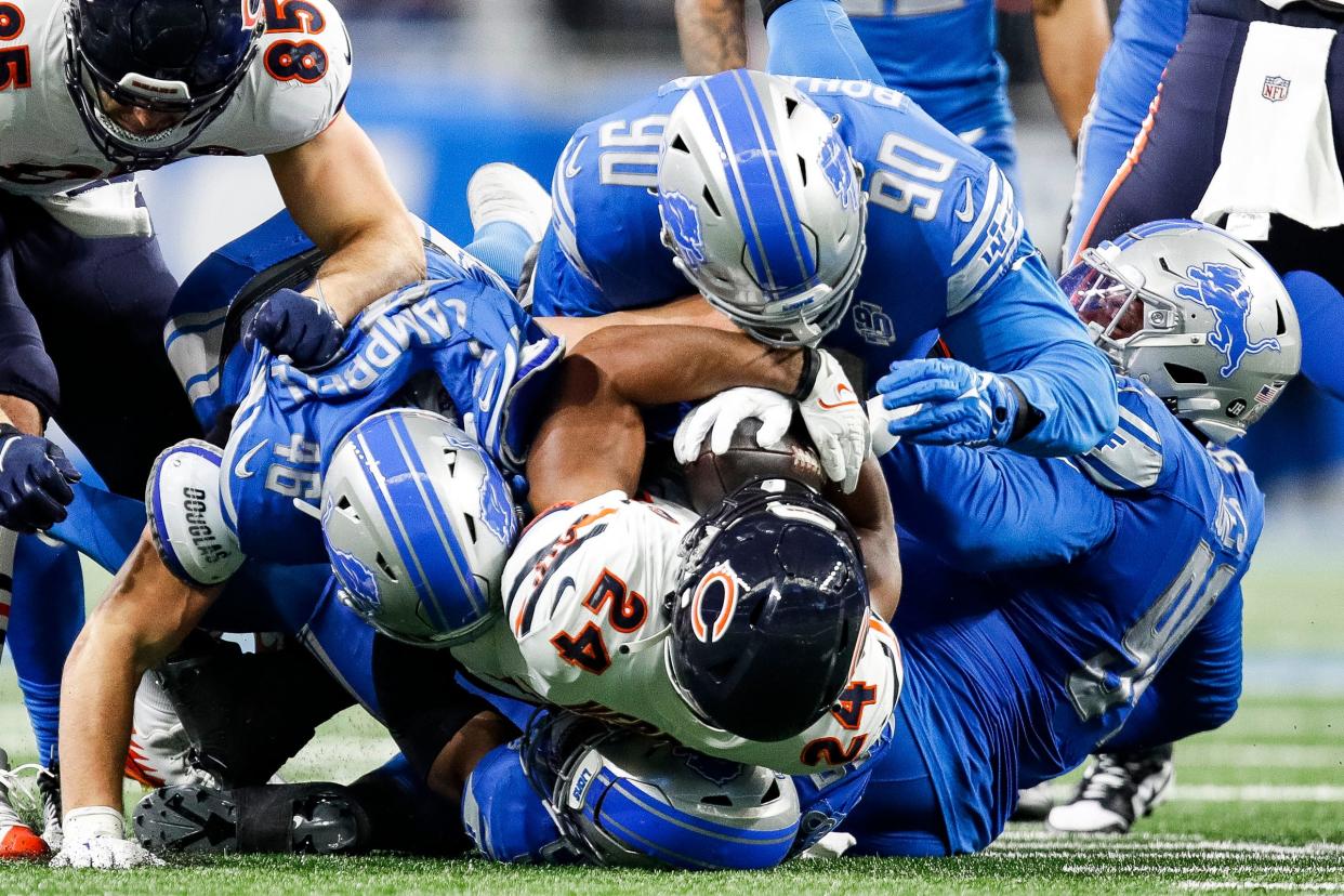 Chicago Bears running back Khalil Herbert is tackled by the Detroit Lions defense, including Quinton Bohanna (90) during the first half at Ford Field in Detroit on Sunday, Nov. 19, 2023.