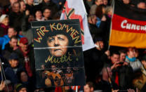 FILE PHOTO: Supporters of the anti-Islam movement Patriotic Europeans Against the Islamisation of the West (PEGIDA) hold a poster depicting German Chancellor Angela Merkel with text reading "We are coming, mommy!" during a demonstration in Dresden, Germany, February 6, 2016. REUTERS/Hannibal Hanschke/File Photo