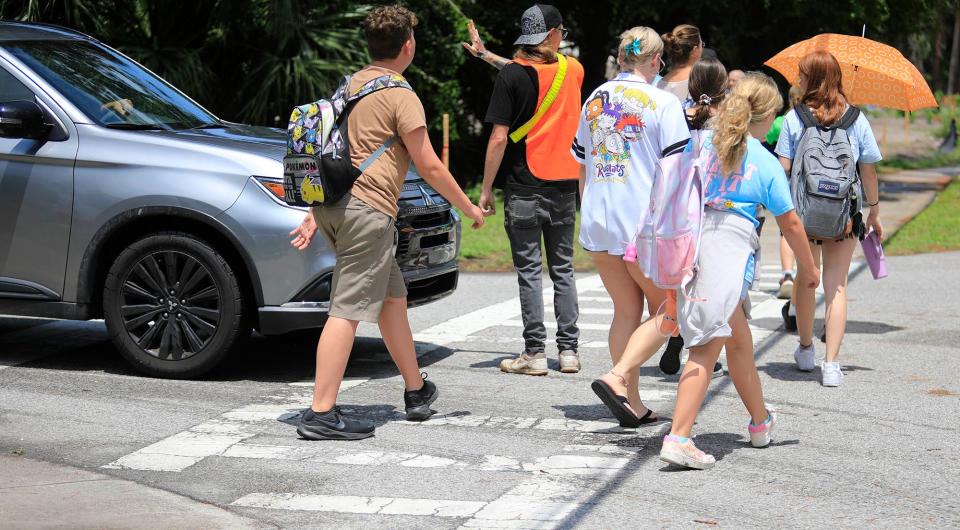 As two unofficial volunteer crossing guards help direct traffic at Sugar Mill Elementary following Friday's fatal accident, a car waits for students and family members to pass, Tuesday, May 28, 2024.