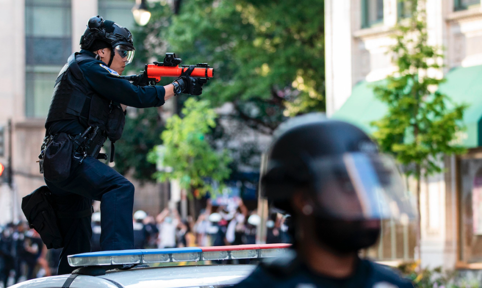 A DC Police officer stands on the back of a police cruiser with smashed windows as he aims a non-lethal launcher at protestors as they clash with Police after the death of George Floyd at the hands of Minneapolis Police in Washington, D.C. on May 31, 2020. (Photo: Samuel Corum / AFP) 