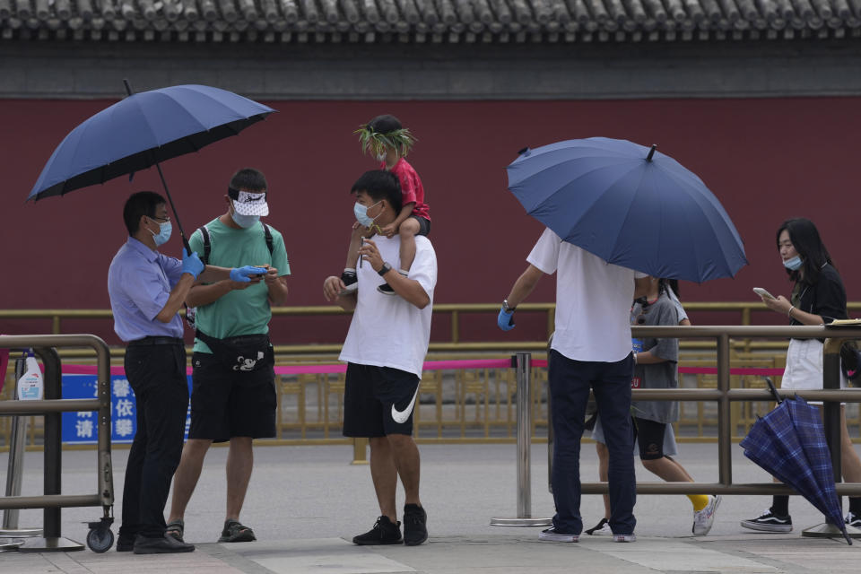 A worker checks the health code of tourists visiting the Summer Palace in Beijing on Aug. 3, 2021. Strict virus control measures have allowed China to return to relatively normal life. The number of tourists visiting Beijing in June and July tripled compared to the same period last year, while revenue quadrupled, according to Trip.com, China's largest online travel booking platform. (AP Photo/Ng Han Guan)