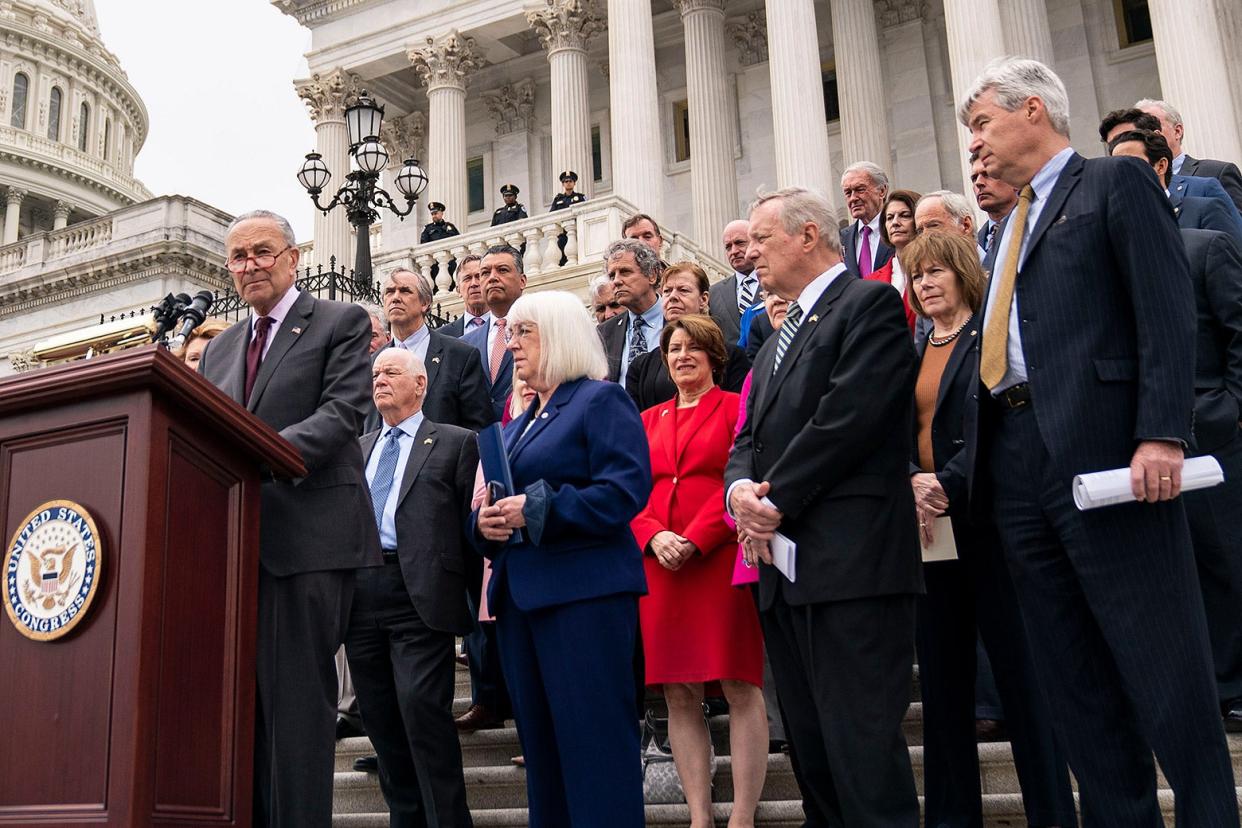 A bunch of senators in suits and pantsuits on the steps of the Capitol building.