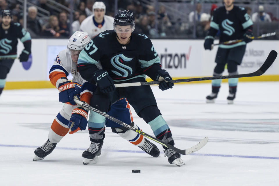 Seattle Kraken forward Yanni Gourde, right, and New York Islanders forward Casey Cizikas battle for the puck during the second period of an NHL hockey game, Sunday, Jan. 1, 2023, in Seattle. (AP Photo/Stephen Brashear)