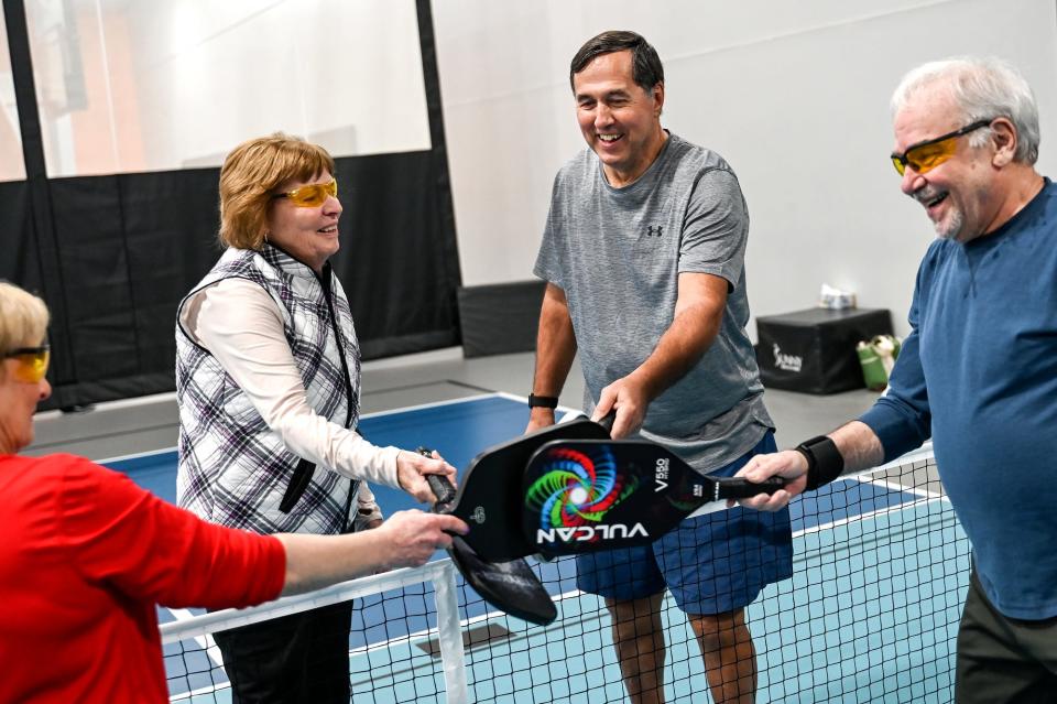 From left, Norma Koob, Linda Wigginton, Gary Beaudoin and Mike Shore slap pickleball paddles at the net after their game on Friday, Jan. 27, 2023, at Court One Athletic Clubs in Lansing.
