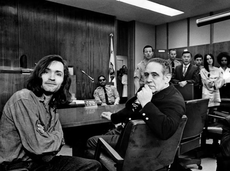 CLAIMS INNOCENCE â€" Charles Manson facing newsmen during a recess in Superior Court hearing into Gary Hinman slaying. Beside him is his attorney, Irving A. Kanarek. Photographer: George R. Fry / Los Angeles Times Date published in LA Times: June 19, 1970