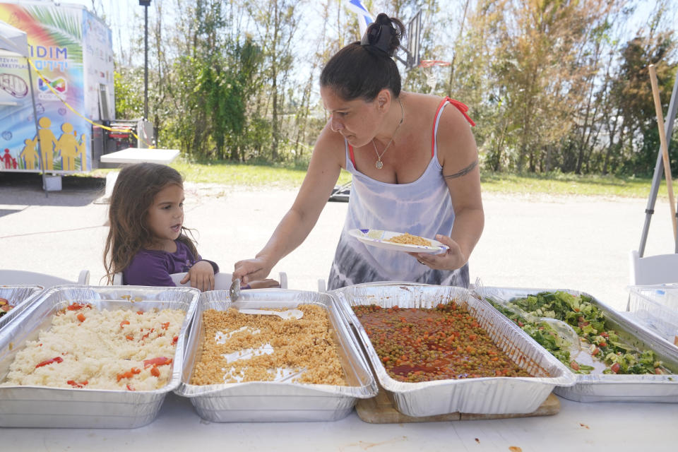 A family serve themselves lunch at the Chabad Lubavitch of Southwest Florida, Monday, Oct. 3, 2022, in Fort Myers, Fla. The synagogue has been transformed into a full-fledged community center with food trucks and a pantry. They plan on celebrating Yom Kippur on Tuesday. (AP Photo/Marta Lavandier)