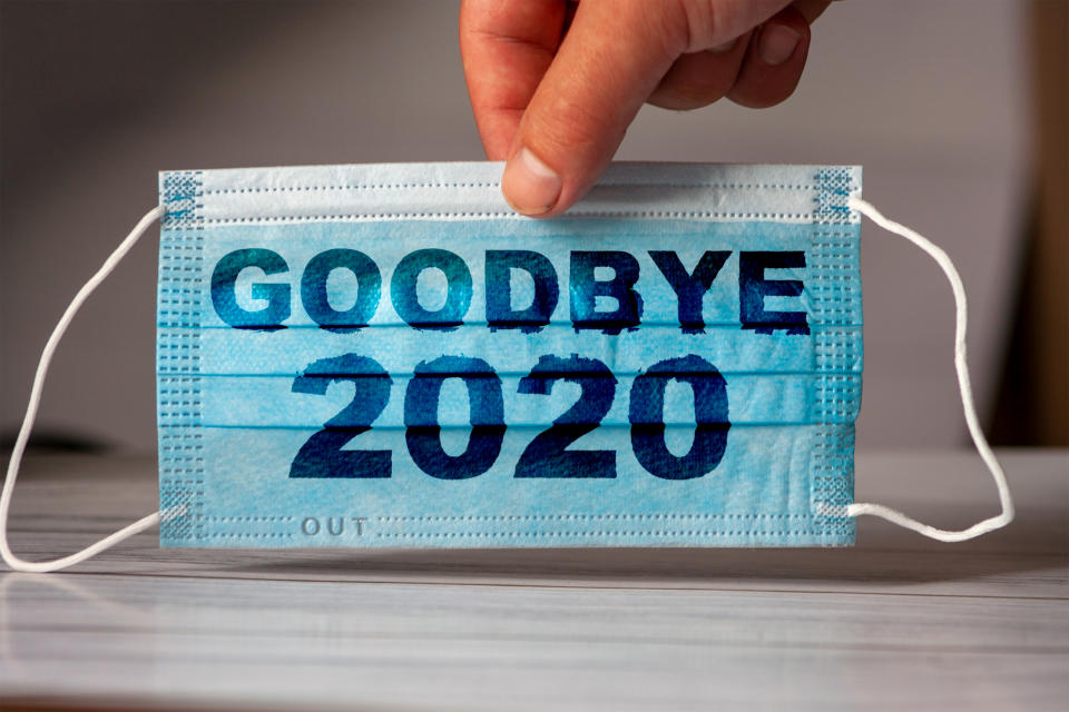 The hand holds a medical and protective mask with the word GOODBYE 2020. Concept of coronavirus quarantine. Prevent or stop the spread of the COVID-19 worldwide.