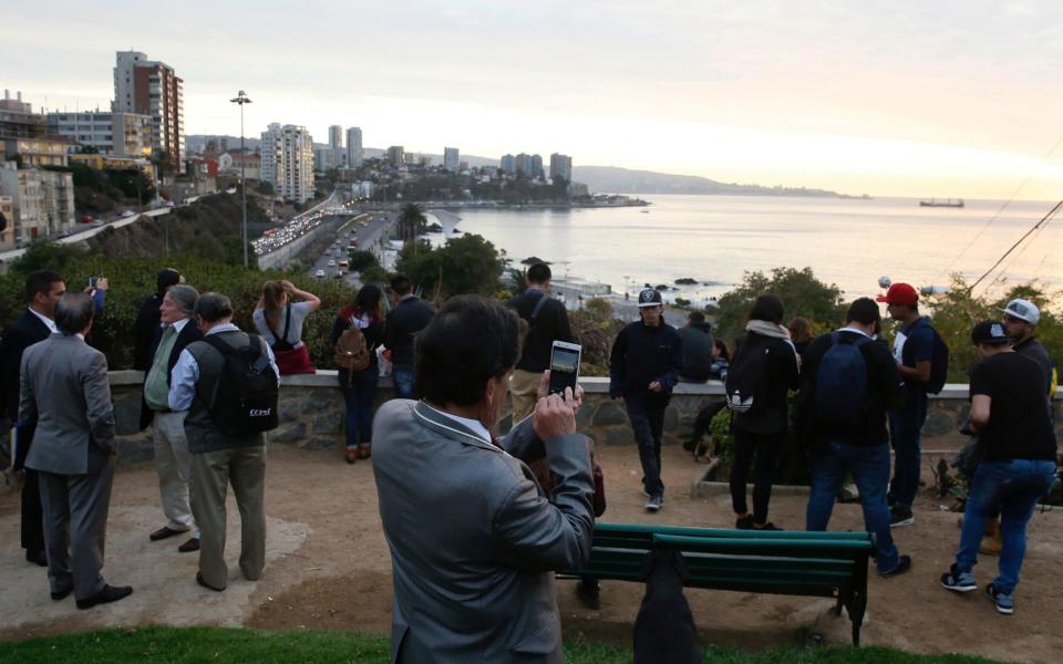 People stand and watch the ocean in Chile before the threat of a tsunami after the 7.1 quake passed - Credit: Reuters