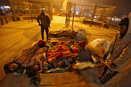 A family gather under blankets to shelter from the cold beneath a flyover in Delhi, India January 16, 2017. REUTERS/Cathal McNaughton