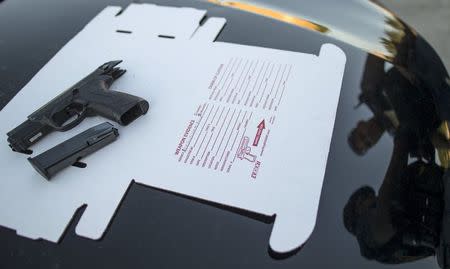 Cook County Sheriff police officers are reflected in the hood of a car as they write up the paperwork for a recovered gun in the Austin neighborhood in Chicago, Illinois, United States, September 9, 2015. REUTERS/Jim Young