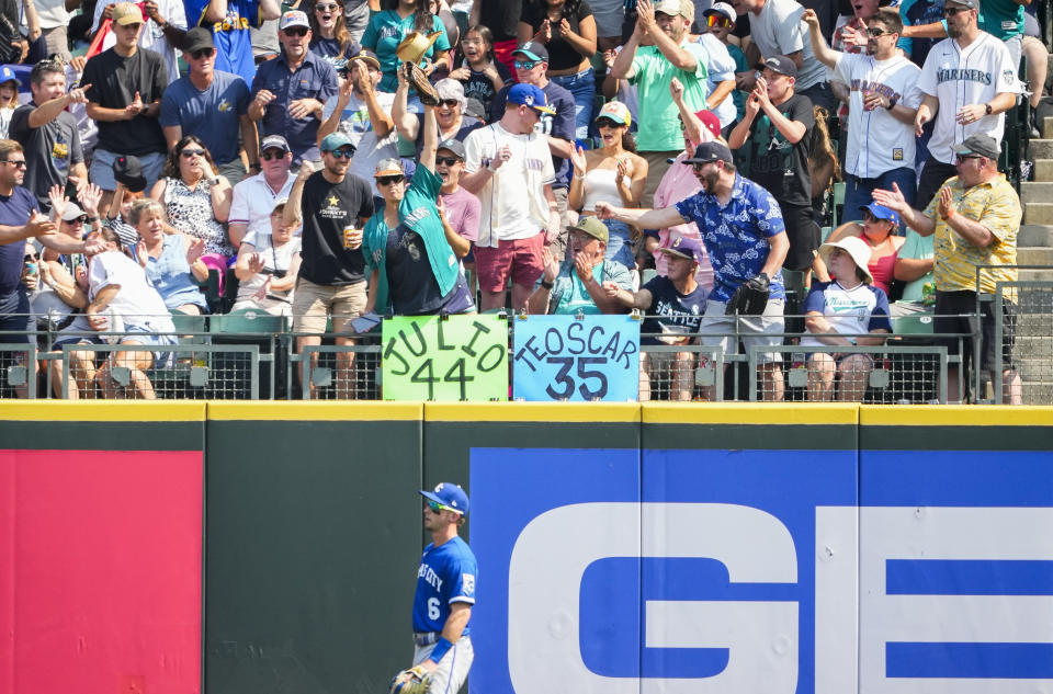 A fan, top left center, holds a two-run home run ball hit by Seattle Mariners' Mike Ford as Kansas City Royals right fielder Drew Waters (6) stands on the warning track during the third inning of a baseball game Saturday, Aug. 26, 2023, in Seattle. (AP Photo/Lindsey Wasson)