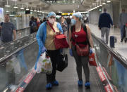 Tourists wearing protective gear against the Covid-19 virus arrive at the Suvarnabhumi Airport in Bangkok, Thailand, Wednesday, March 4, 2020. (AP Photo/Sakchai Lalit)