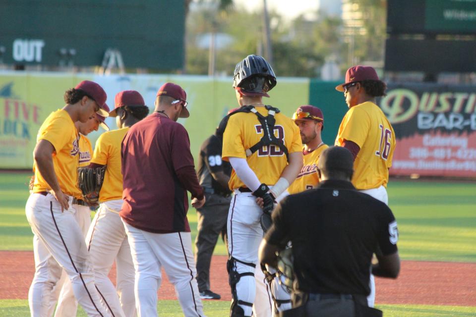 B-CU coach Johnny Hernandez (maroon jacket) meets his team on the mound Tuesday night during another pitching change. B-CU and Stetson combined to use 11 pitchers.