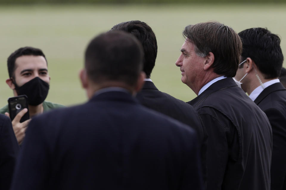 Brazil's President Jair Bolsonaro, second from right, talks with supporters, some wearing face masks amid the new coronavirus pandemic, as he leaves his official residence, Alvorada palace, in Brasilia, Brazil, Monday, May 25, 2020. (AP Photo/Eraldo Peres)