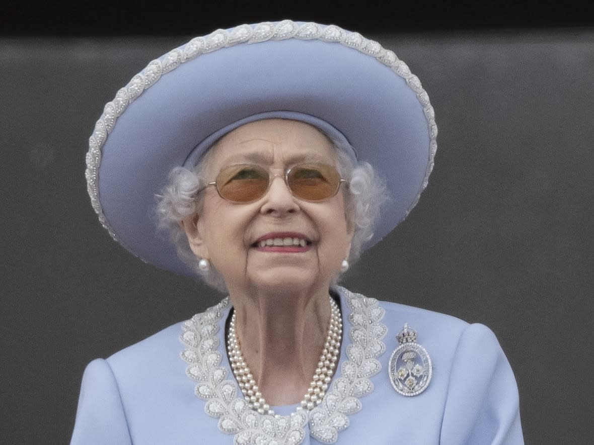 Queen Elizabeth II stands on the balcony of Buckingham Palace, London, as she watches a flypast of Royal Air Force aircraft Thursday.   (Paul Grover/The Associated Press - image credit)
