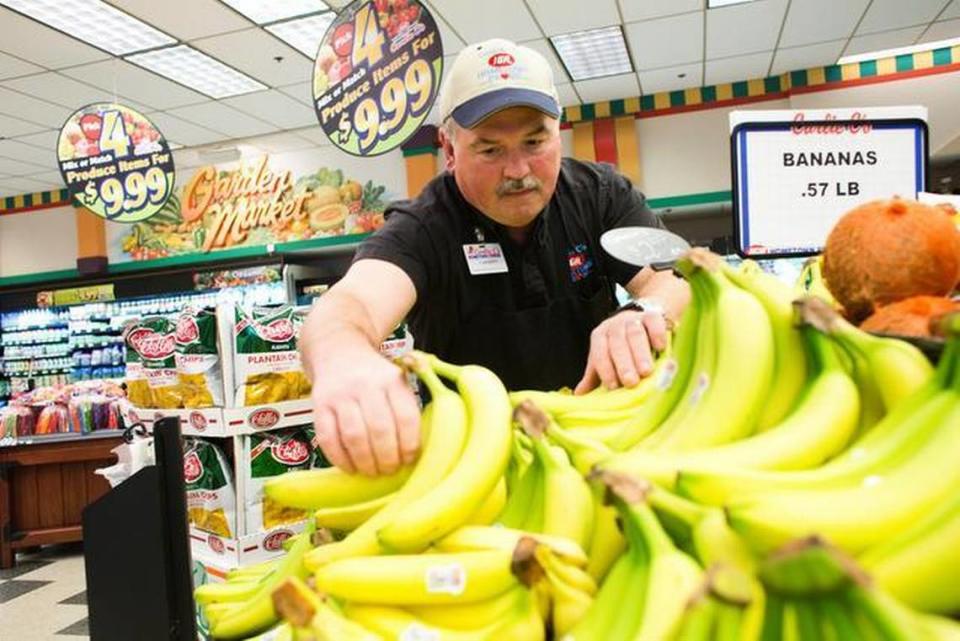 Produce manager Tracy Massey stocks bananas in September at the Carlie C’s IGA on New Bern Avenue in Raleigh.