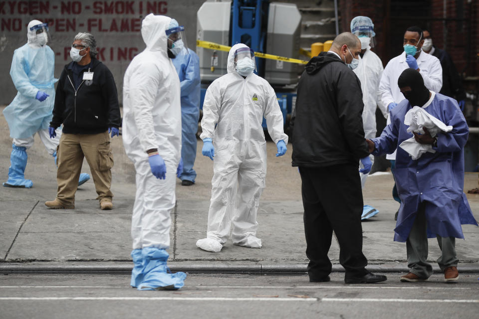 Medical workers wearing personal protective equipment due to COVID-19 concerns pause for rest before loading bodies onto a refrigerated container truck functioning as a makeshift morgue, Tuesday, March 31, 2020, at Brooklyn Hospital Center in Brooklyn borough of New York. The new coronavirus causes mild or moderate symptoms for most people, but for some, especially older adults and people with existing health problems, it can cause more severe illness or death. (AP Photo/John Minchillo)